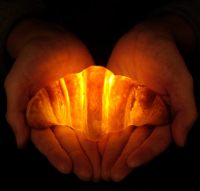 Battery operated croissant lamp, illuminated, in model's hands