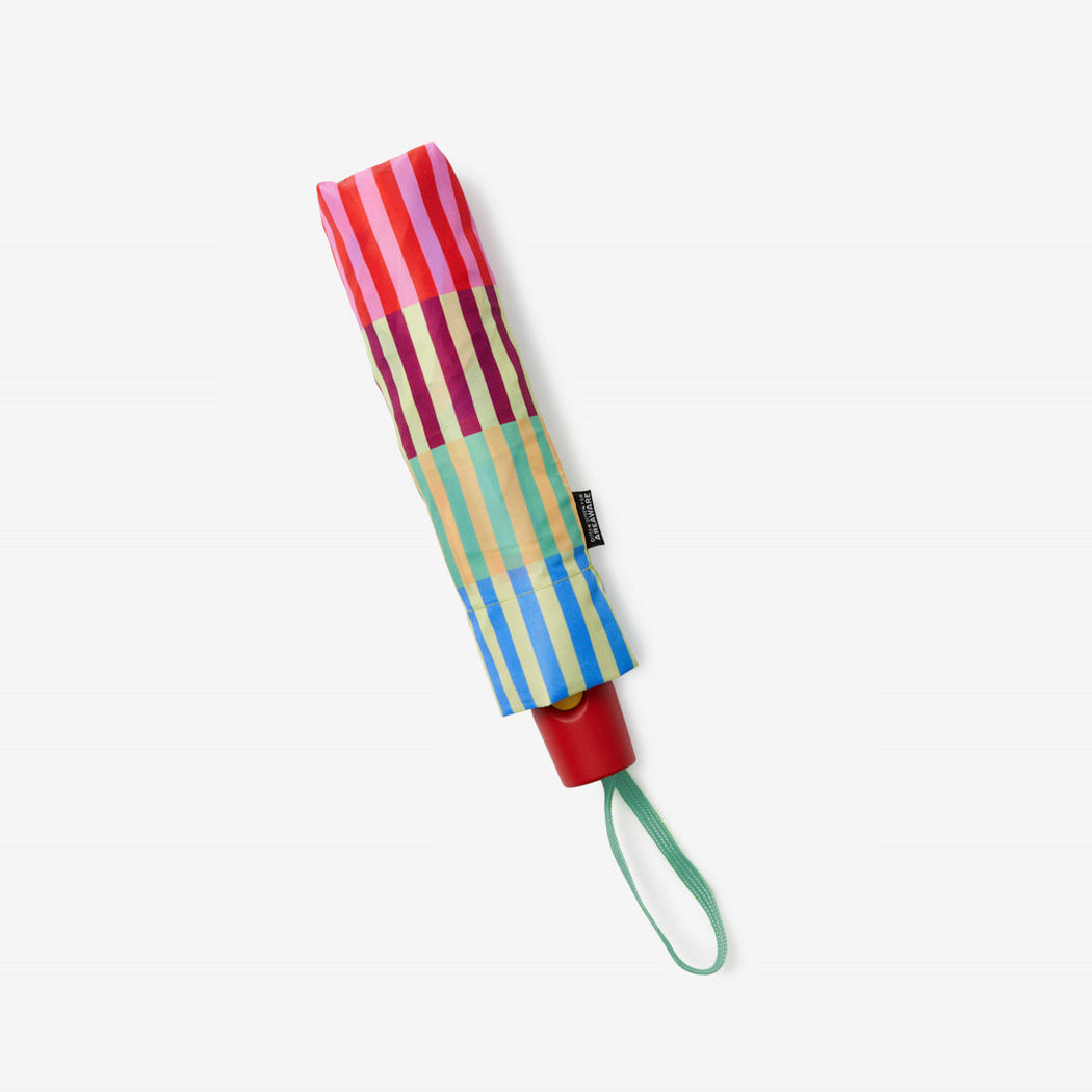 Red umbrella handle sticking out of a multi-color striped fabric umbrella case