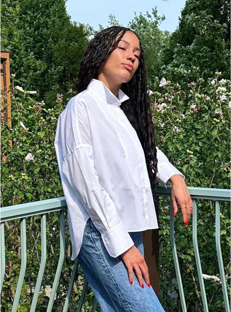 female model wearing white long sleeve shirt with pleated front bib, wing collar, hidden buttons & curved hem