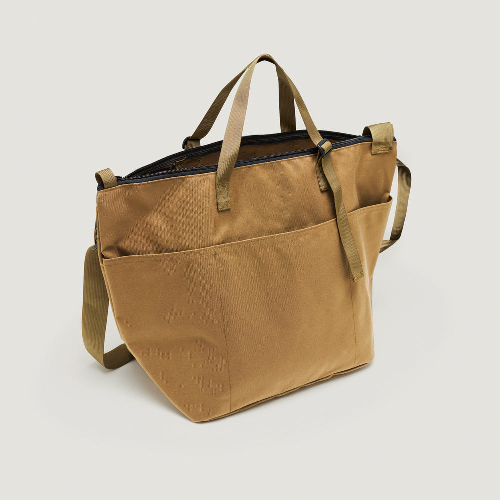 Khaki colored canvas tote bag with exterior pockets, adjustable nylon webbing handle & shoulder strap, and  zipper closure (back view)
