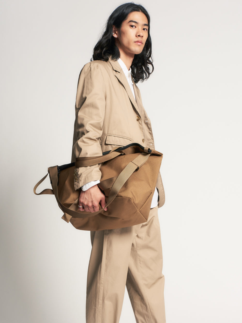 Male model holding khaki colored canvas tote on his hip