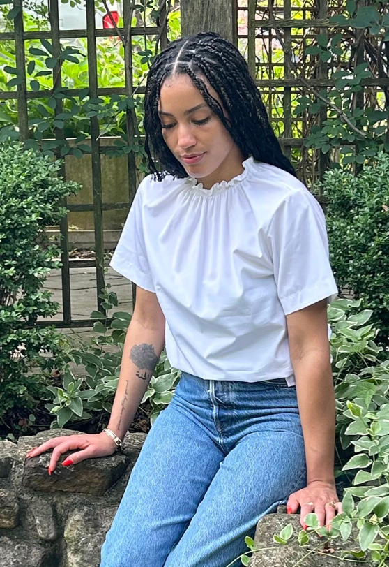 Female model wearing short sleeve white shirt with ruched neckline  & denim pants