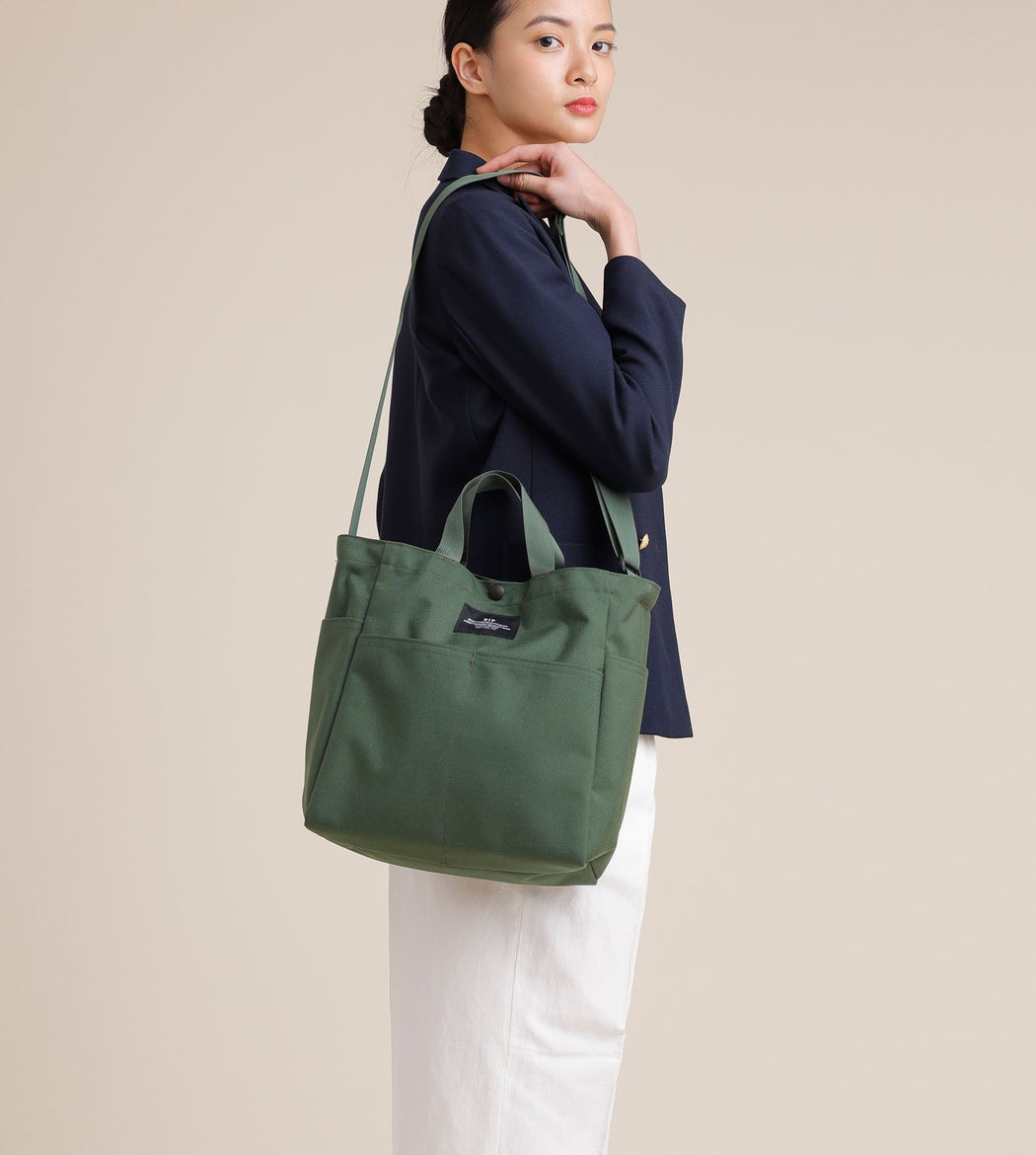 Female model wearing olive green canvas tote with shoulder strap