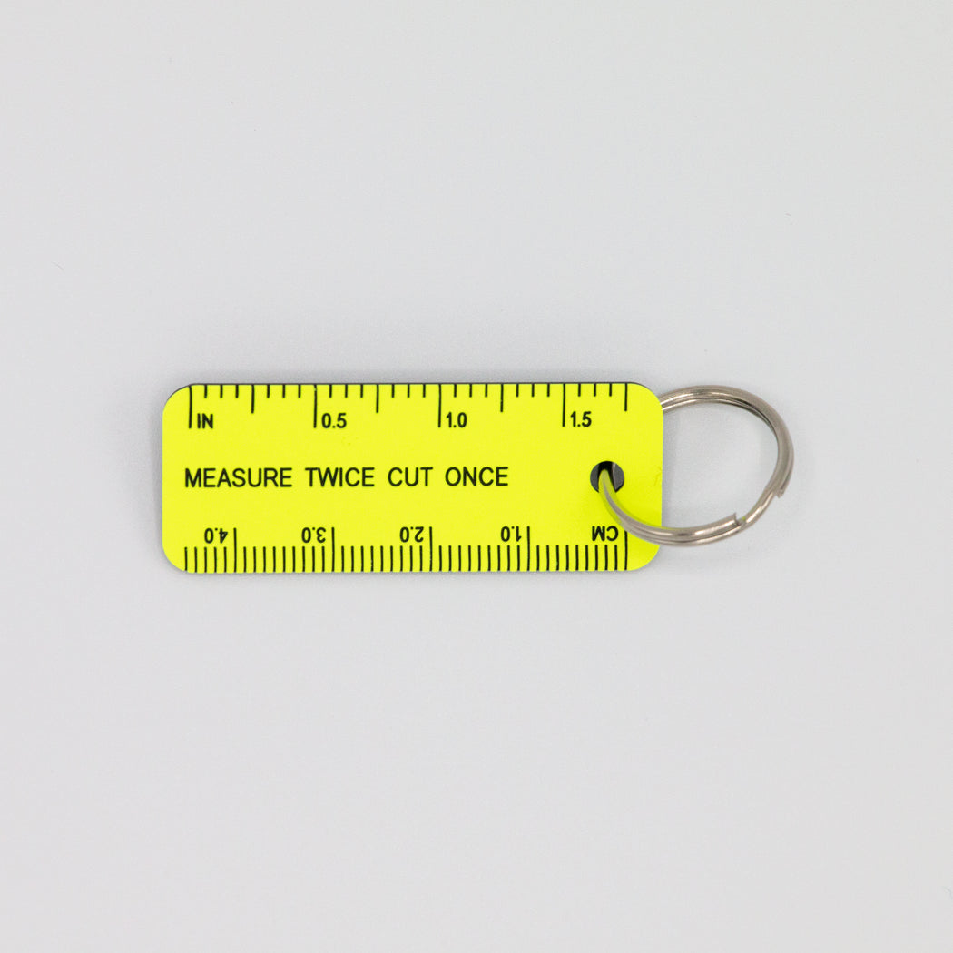 Yellow rectangular key tag with ruler markings, reading "MEASURE TWICE CUT ONCE"