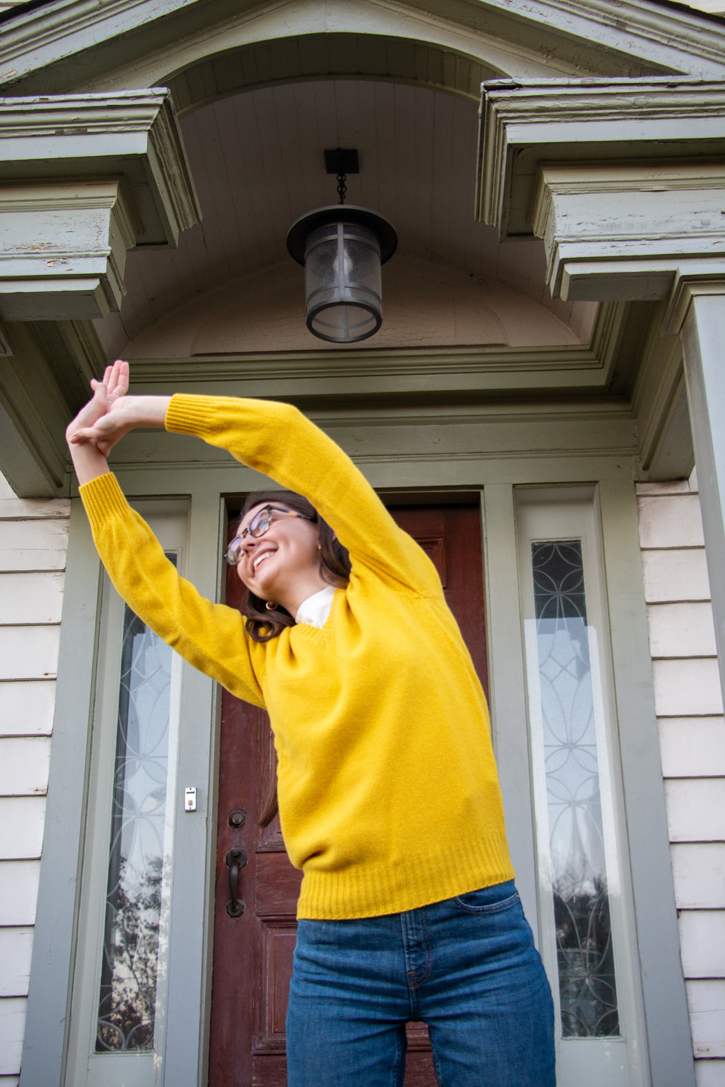 Female model wearing yellow long sleeve V-neck sweater & jeans