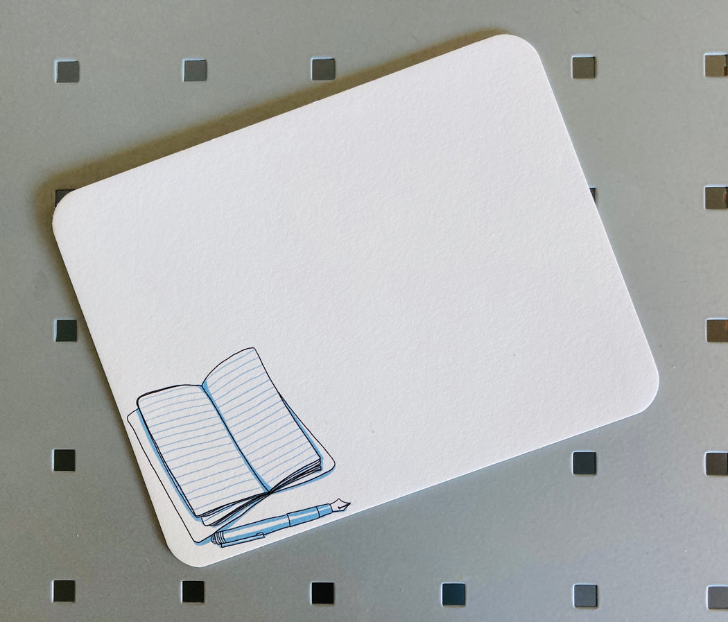 White note card with illustration of an open journal & pen on bottom left corner