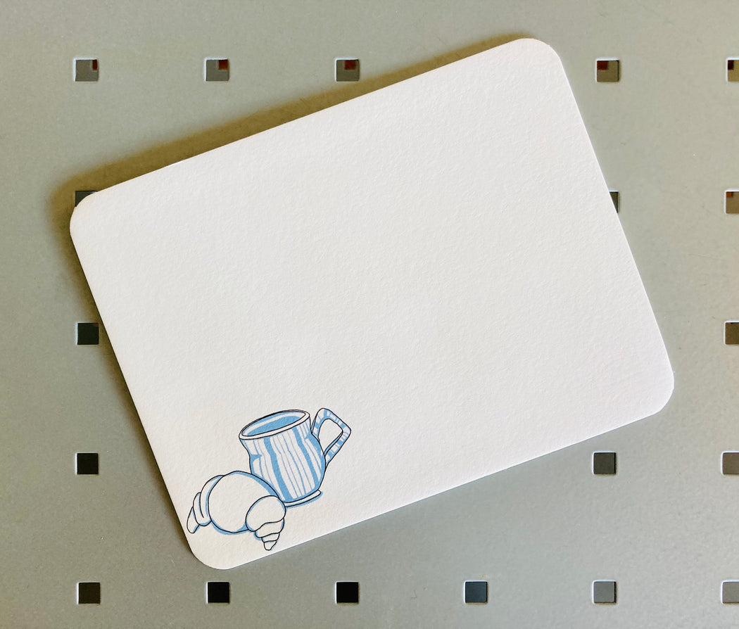 White note card with illustration of a croissant & coffee mug on bottom left corner