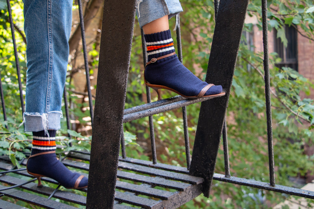 Model wearing navy tube socks with orange & white stripes and high heels
