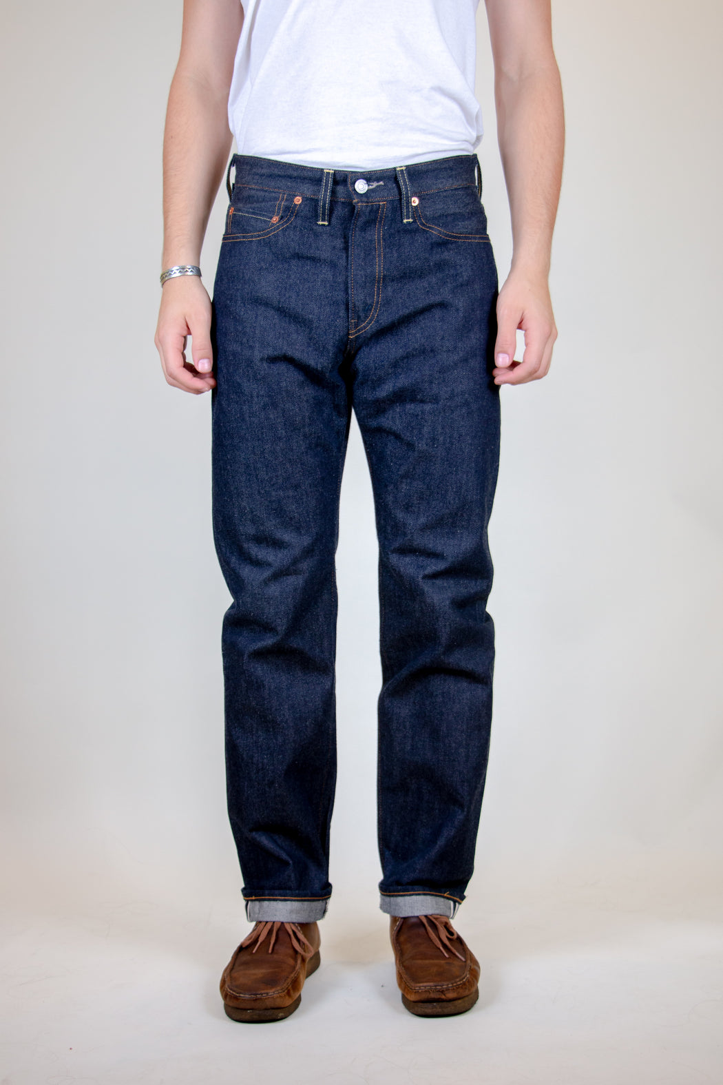 Man wearing dark blue Levi’s vintage 501 raw denim men’s jeans with white t-shirt tucked in.