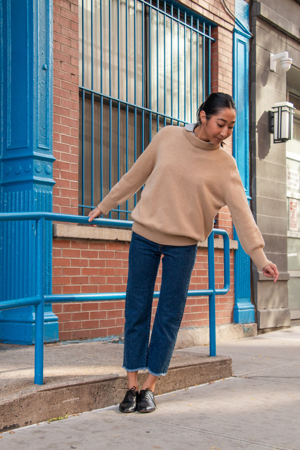 Model wearing tan long sleeve sweater with high neck
