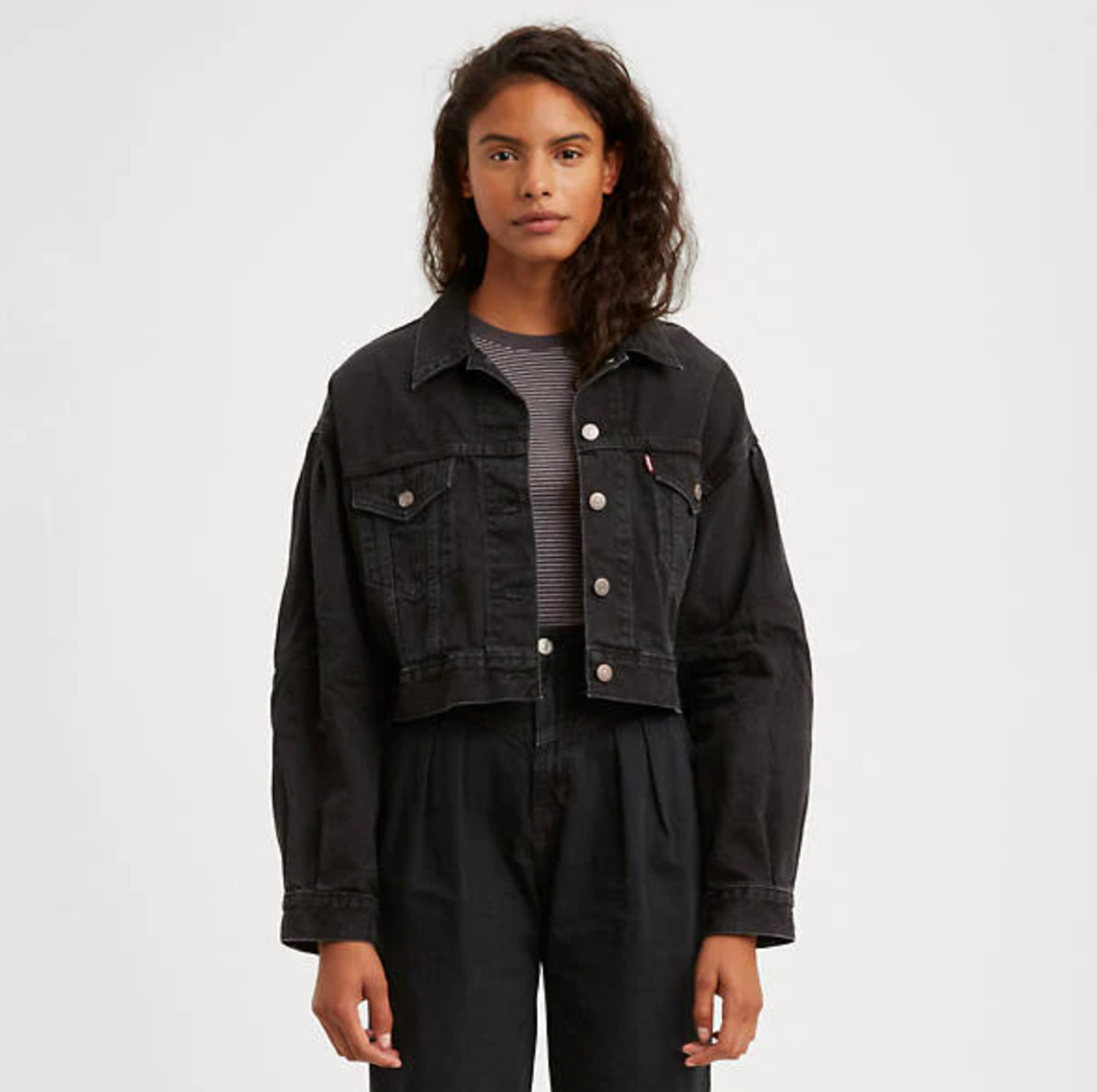 Model wearing black cropped jean jacket with front button flap pockets