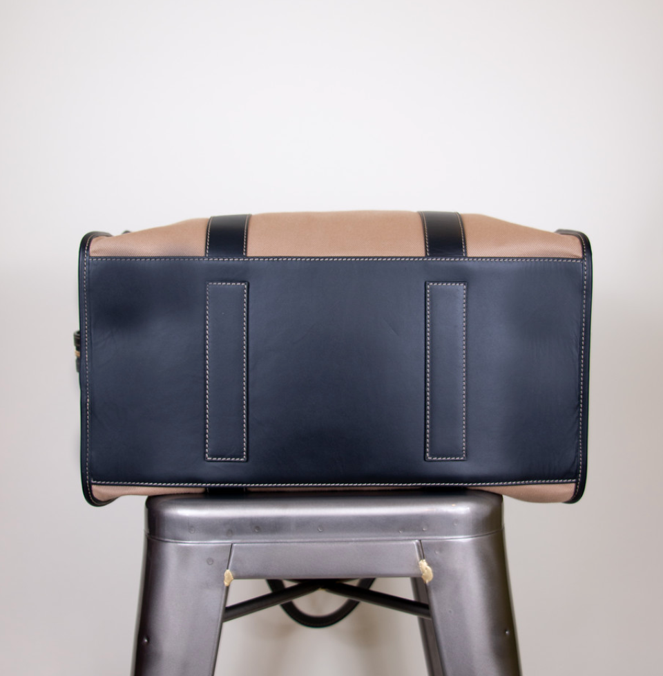 Black leather bottom of tan cotton twill weekender bag