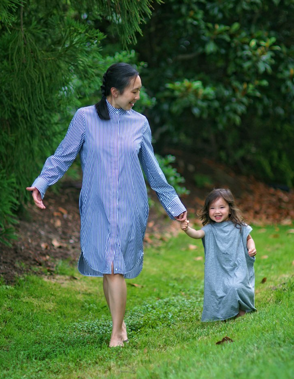 Female model wearing blue & white striped long sleeve shirtdress, walking with small child