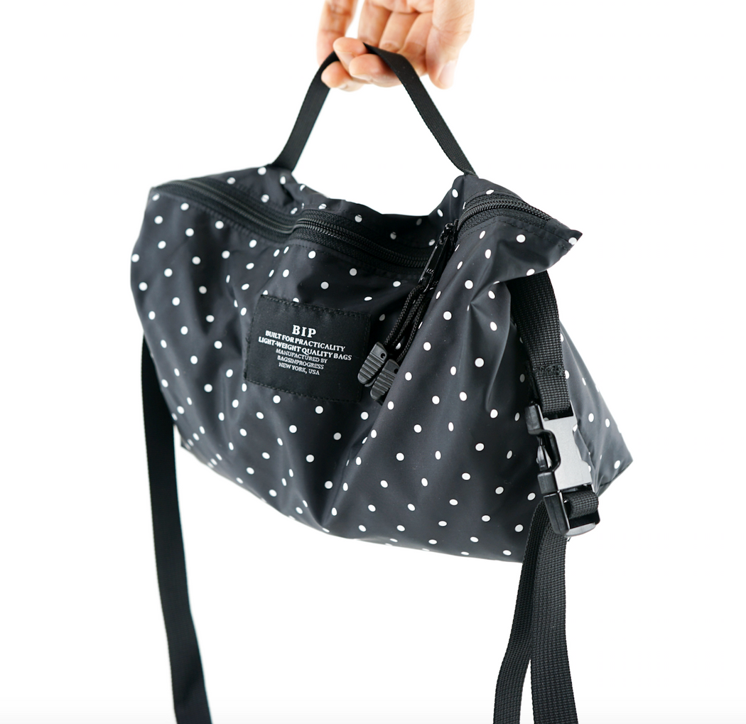 Hand held black and white dot nylon fanny pack with zip closure and adjustable black strap