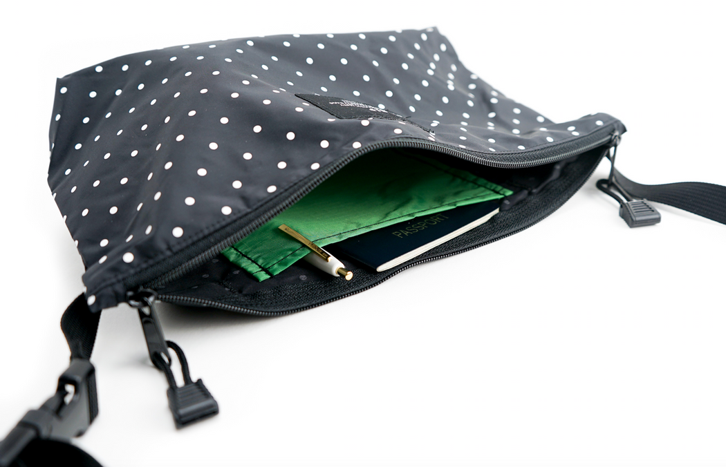 Interior view: Black and white dot nylon fanny pack with open zip top and  interior green pocket