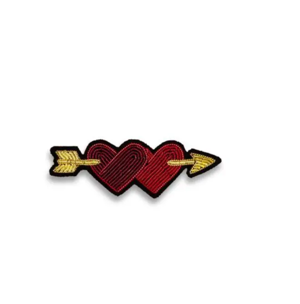 An embroidered pin showing two red hearts with a yellow arrow going through them