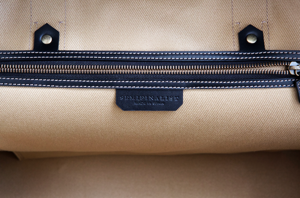 Interior brass zipper pocket detail with SemiFinalist logo, tan fabric with black trim