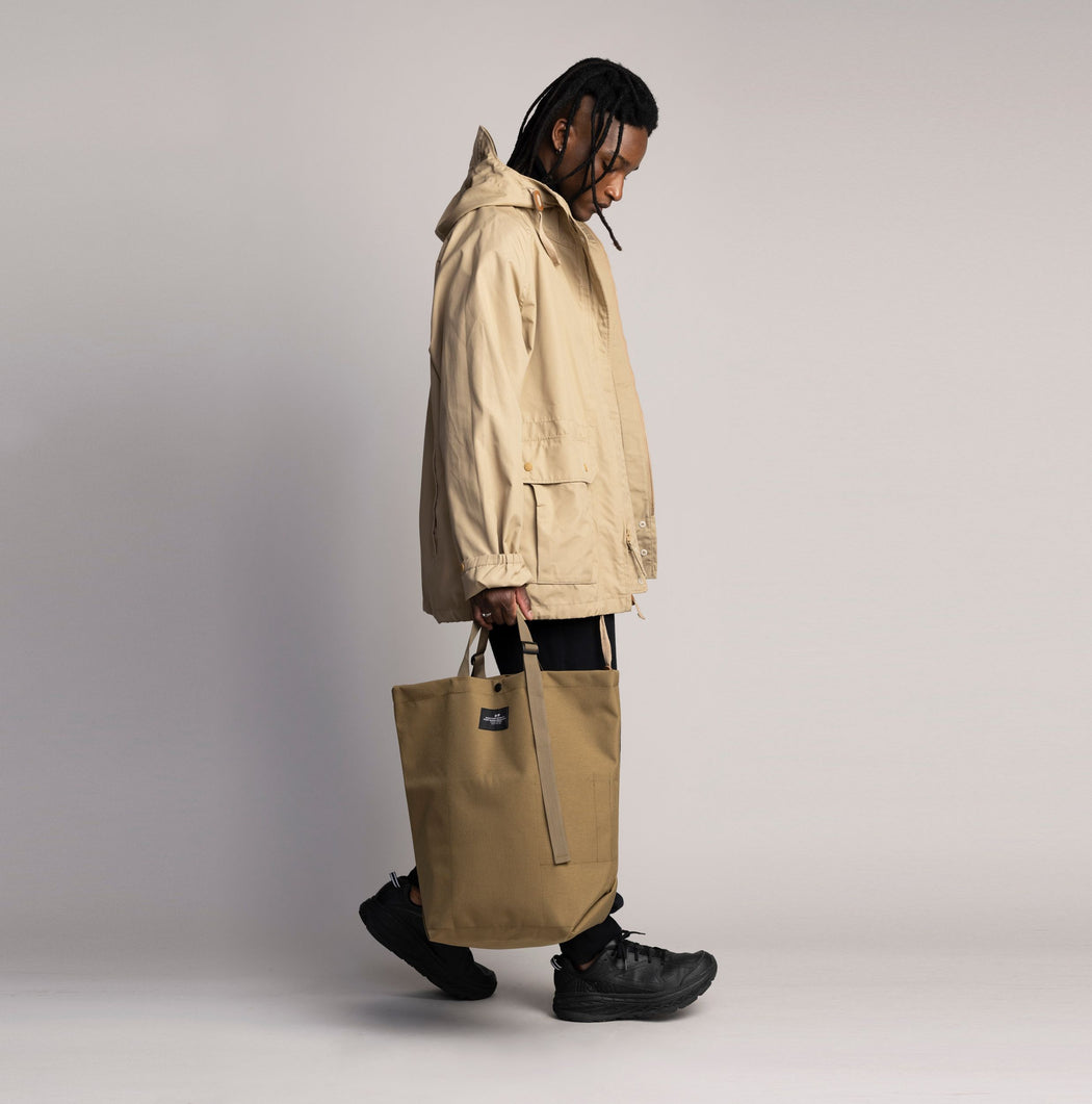 Male model holding the Khaki Carry-All Tote by the handles