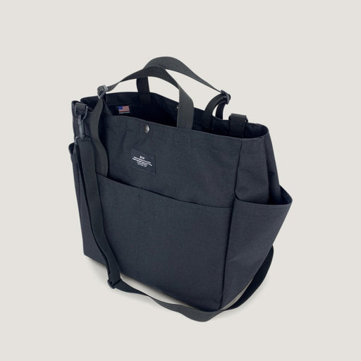 Large black tote bag with snap closure, exterior pockets, handles & shoulder strap (3/4 view)