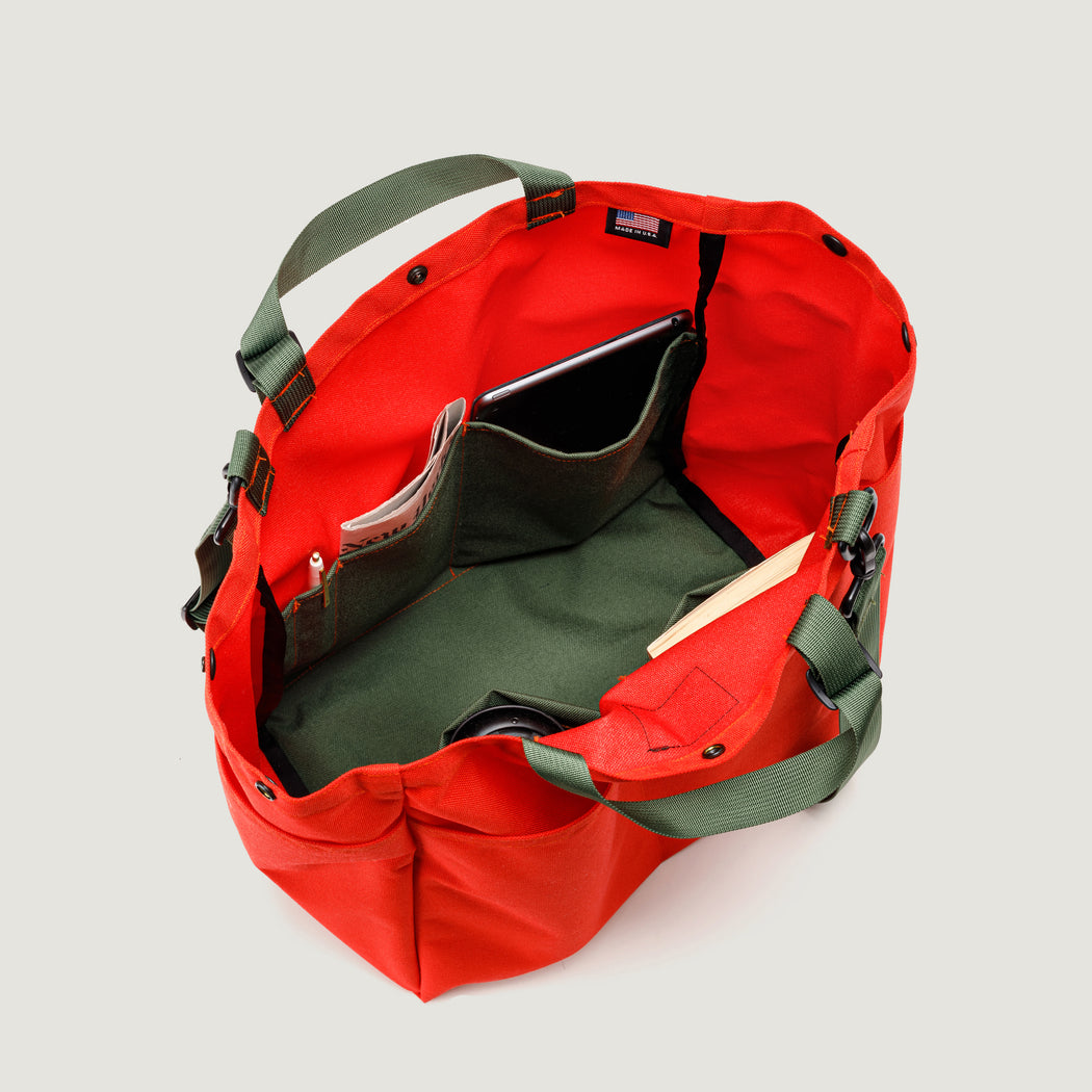 Interior view: Large reddish-orange tote bag with snap closure, olive green interior organization pockets, and handles