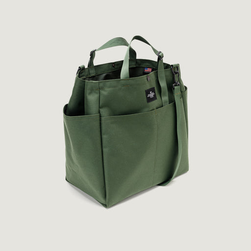 Olive colored tote bag with snap closure, exterior pockets, top handles & shoulder strap (three quarter view)