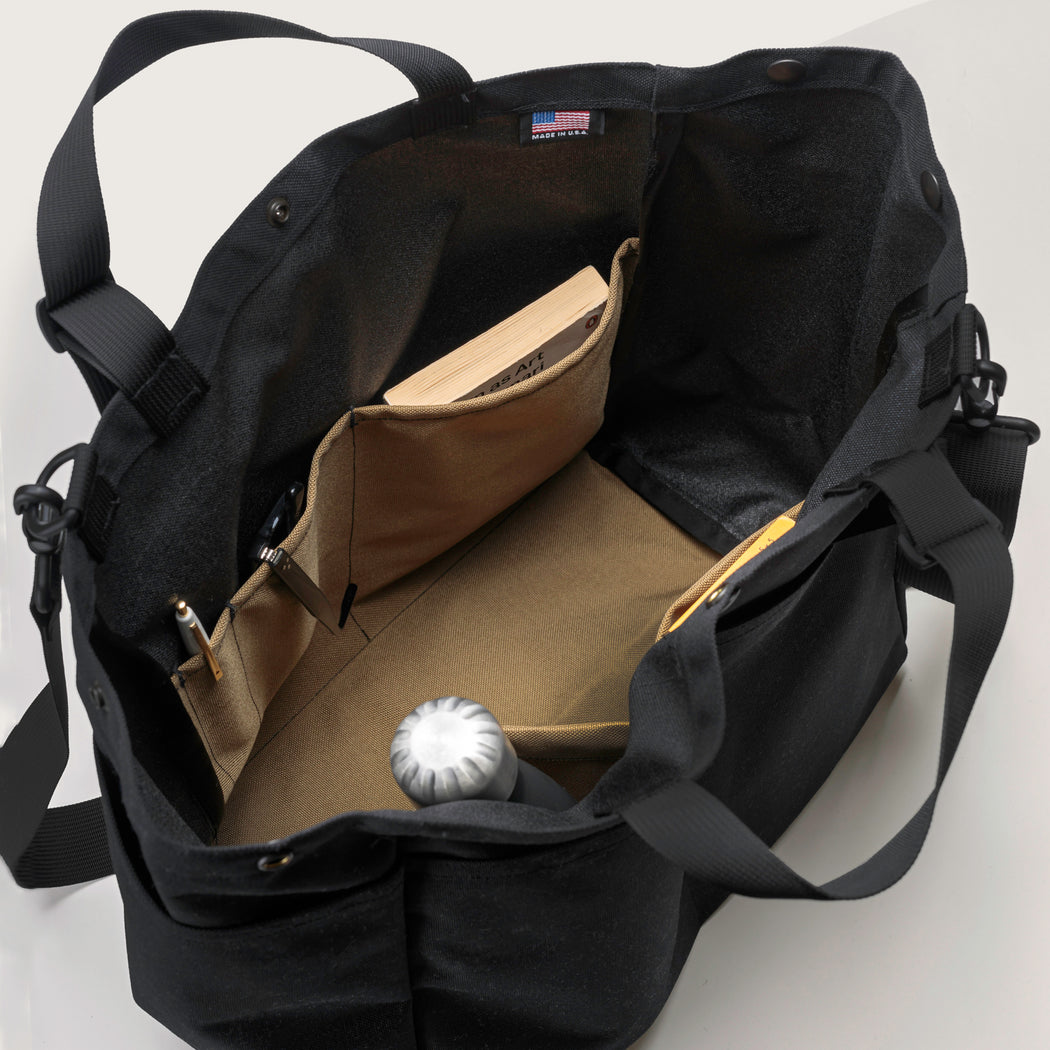 Black tote bag with snap closure, top handles & shoulder strap (tan interior view with organization pockets)