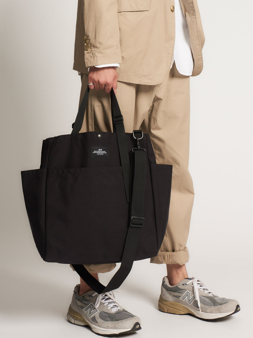 Model holding black canvas tote bag by handles