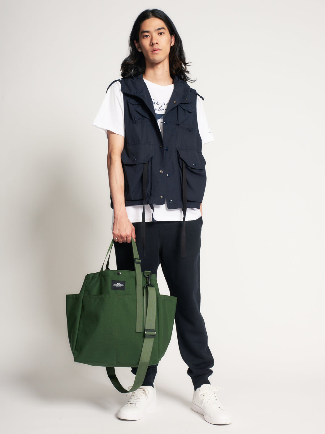 Male model holding olive green colored canvas tote bag by the handles 