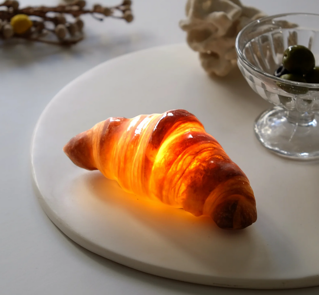 Battery operated croissant lamp, illuminated, on white plate