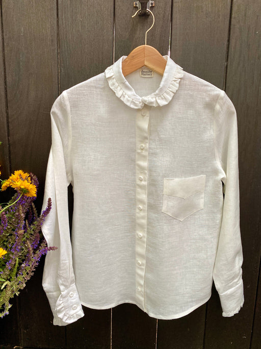 White long sleeve linen blouse with button closures, one front pocket, and ruffled collar and cuff