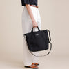 Female model holding black canvas tote with handles & shoulder strap