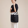Female model wearing black canvas tote with shoulder strap 