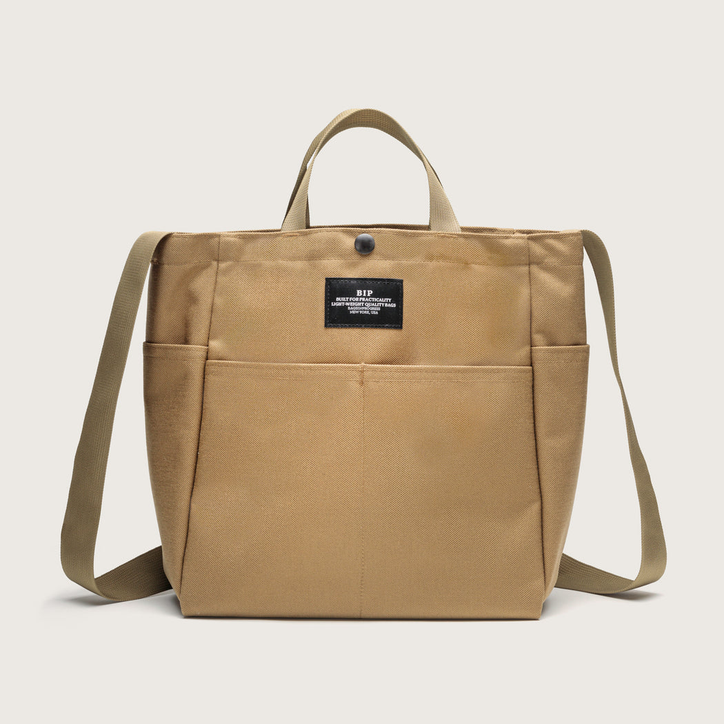 Khaki colored  canvas tote with 4 exterior pockets, snap closure, handles & shoulder strap, front view
