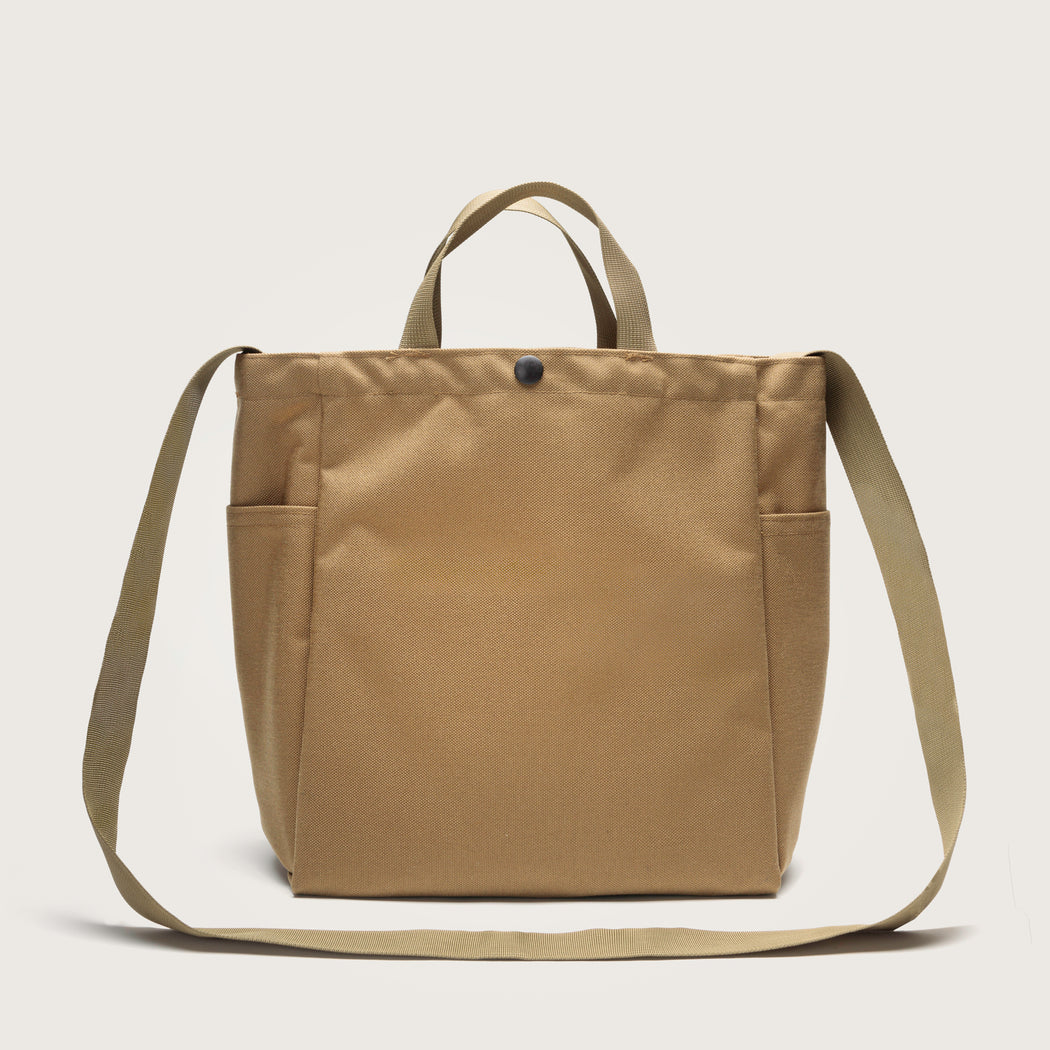 Black canvas tote with 4 exterior pockets, snap closure, handles & shoulder strap, back view