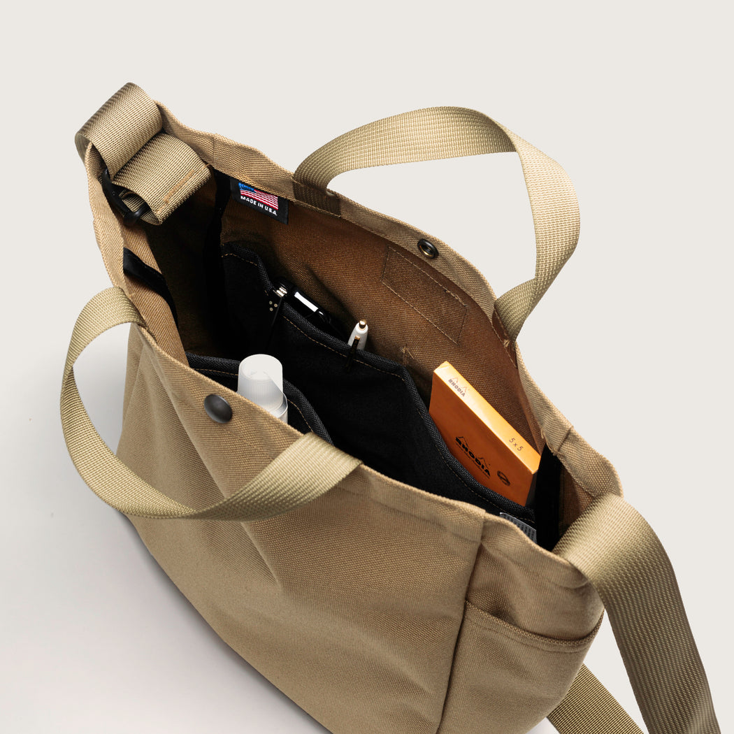 Khaki colored canvas tote interior view, featuring 3 large organization pockets in  contrasting black canvas