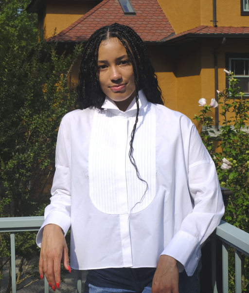 female model wearing white long sleeve shirt with pleated front bib, wing collar, hidden buttons & curved hem