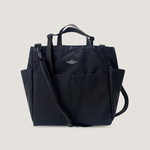 Large black tote bag with snap closure, exterior pockets, handles & shoulder strap (front view)