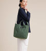 Female model wearing olive green canvas tote with shoulder strap