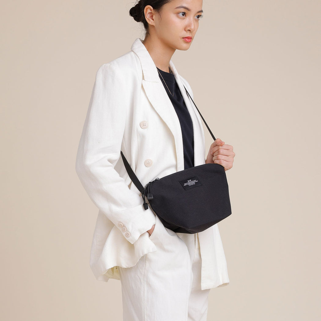 Female model wearing black nylon canvas bag in crossbody manner