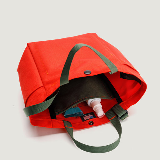 Reddish-orange canvas tote with snap closure, olive green handles & straps & interior olive green pocket