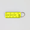 Yellow rectangular key tag with ruler markings, reading "MEASURE TWICE CUT ONCE" 
