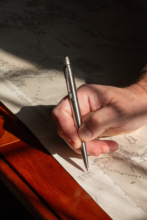 Man holding stainless steel Parker ball point pen writing on map