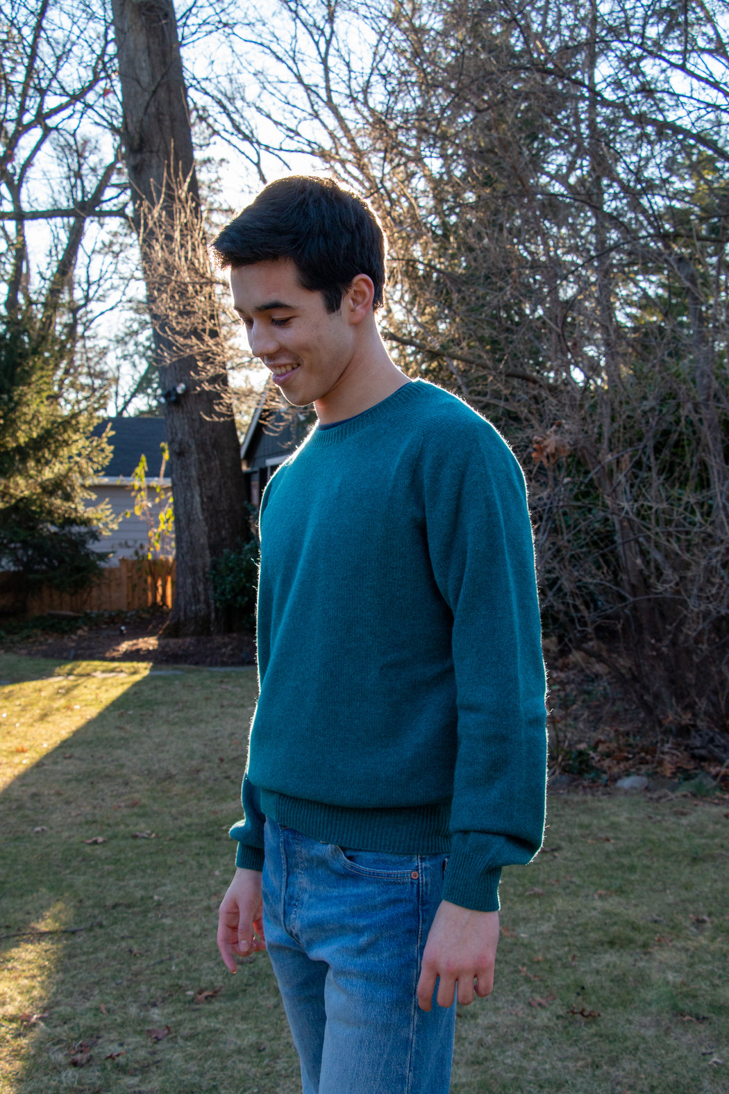 Male model wearing blue long sleeve crew neck sweater with jeans