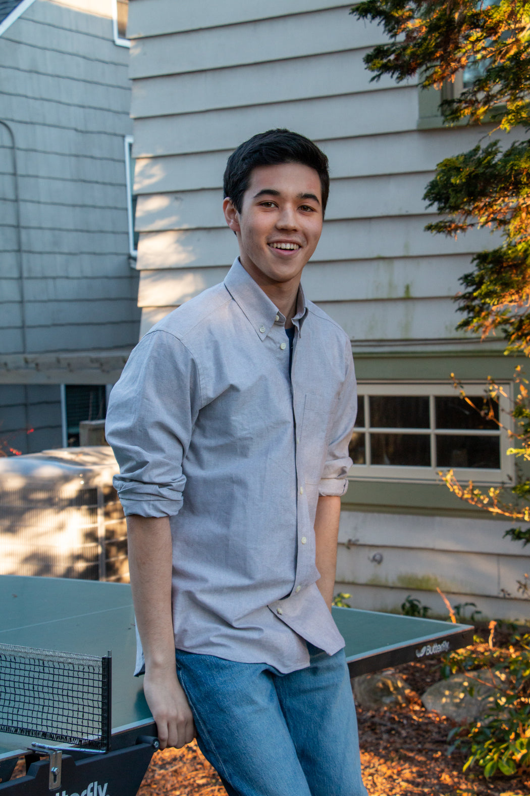 Model wearing sage colored button-down collar shirt with front pocket and rolled up sleeves 