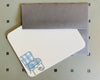 Grey envelope & white note card with illustration of an upholstered chair & slippers on bottom left corner