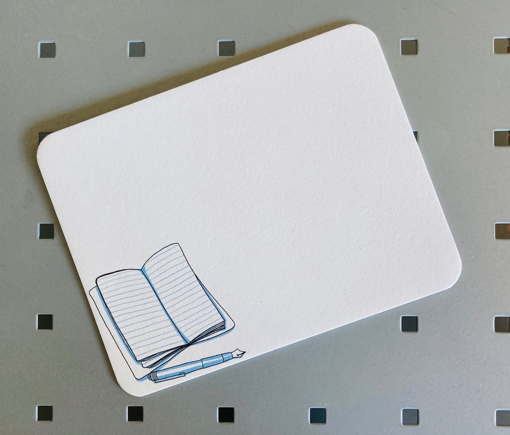 White note card with illustration of an open journal & pen on bottom left corner 