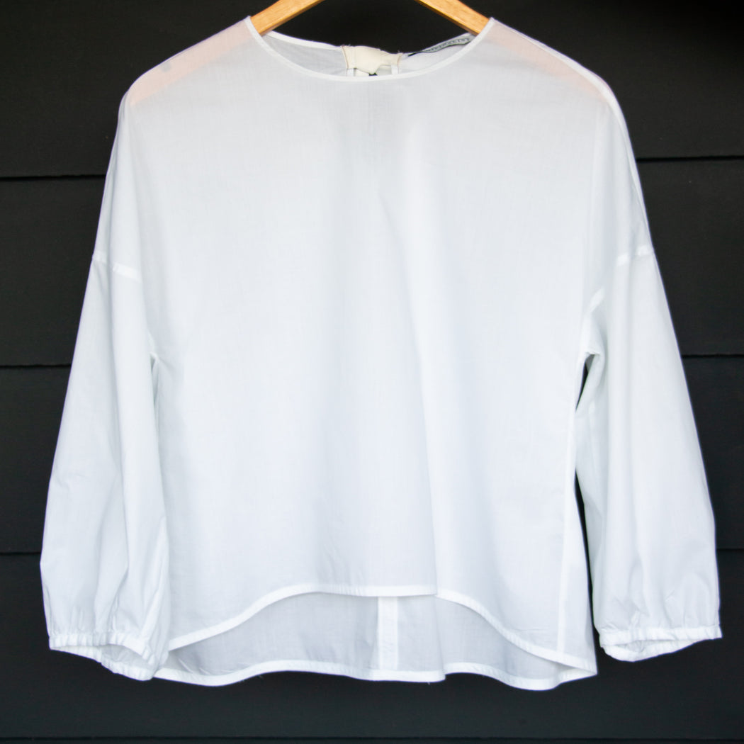 White semi-sheer popover shirt with long puffy sleeves on wooden hanger