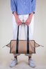 Model holding tan cotton twill weekender bag with leather handles 