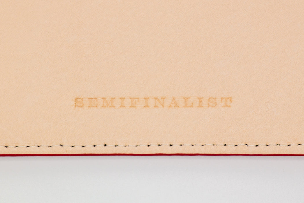 close up of semifinalist logo on tan and red leather file folder