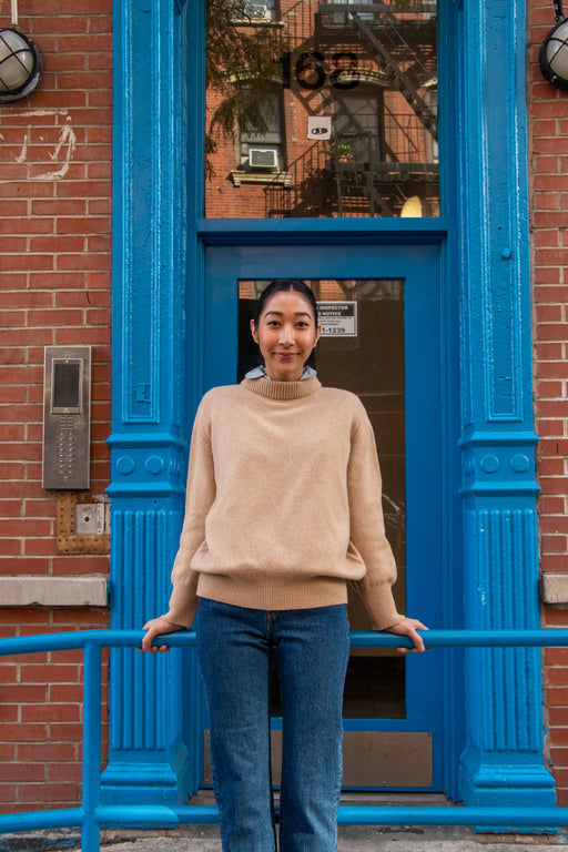 Model wearing tan long sleeve sweater with high neck